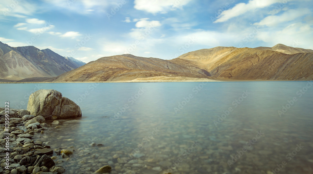Obraz premium india, It is 134 km long and extends from India to Tibet. Leh, Jammu and Kashmir, ladakh, Pangong tso (Lake) with blue sky in background. It is huge lake in Ladakh, scenic