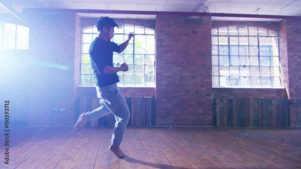 Asian martial artist training alone, practising moves in industrial building Asian martial artist training alone, practising moves in industrial building