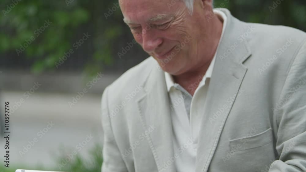 Portrait of happy mature man using computer tablet in urban park area Portrait of happy mature man using computer tablet in urban park area