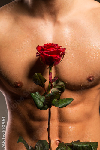 Man with muscular torso holding rose
