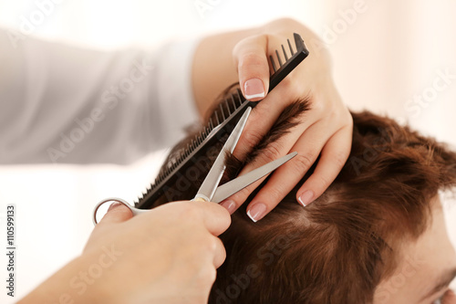 Professional hairdresser making stylish haircut, closeup