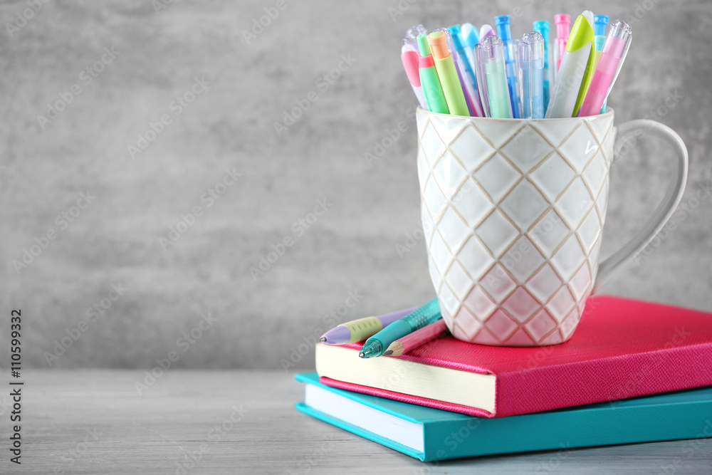 Obraz premium Pens in ceramic cup on grey background