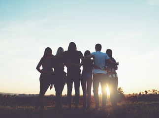 Group of people hugging outdoors; sunset 