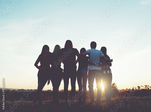 Obraz na plátně Skupina lidí, objímání venku; západ slunce