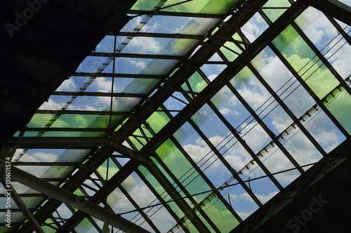 Green glass roof detail of train station over blue sky, Bangkok