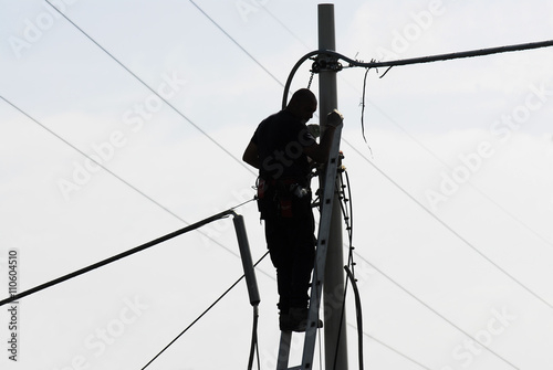 Elettricista lavoro all'aperto, su scala e palo elettrico, con cielo azzurro photo