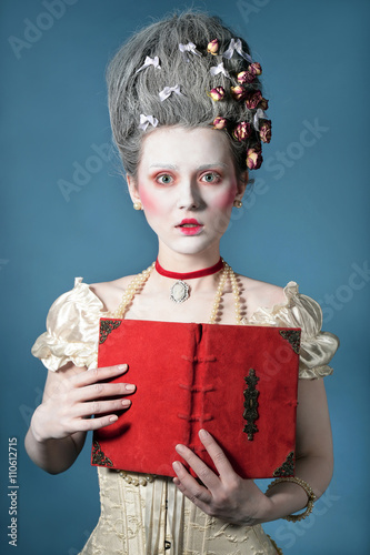 Baroque Style - amazed young woman with vintage red book posing over blue background in elegant light corset with lace. Renaissance. Rococo. Fashion.