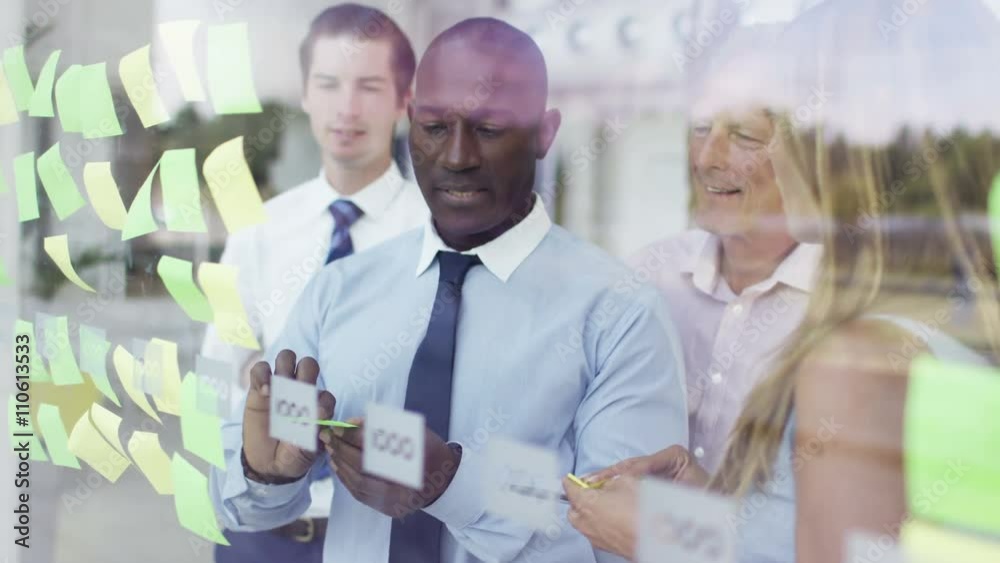Mixed ethnicity business team brainstorming for ideas with sticky notes Mixed ethnicity business team brainstorming for ideas with sticky notes