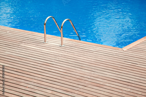 Blue swimming pool with teak wood floor stripes summer vacation