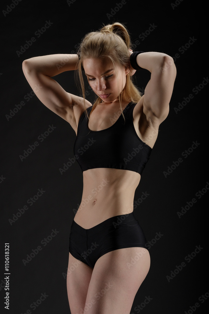 Young muscular woman posing on black