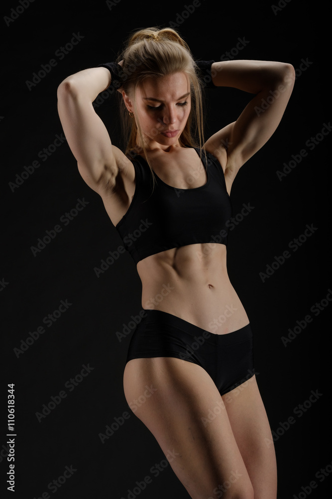 Fototapeta premium Young muscular woman posing on black