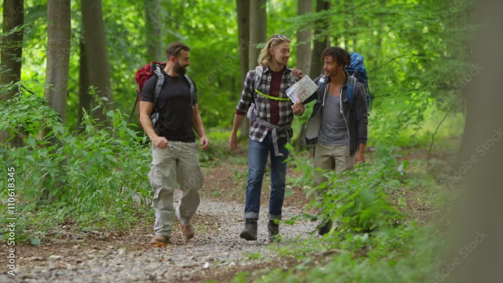 Group of male friends hiking in the woods holding map and trying to find their way. Group of male friends hiking in the woods holding map and trying to find their way.