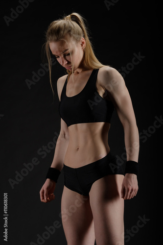 Young muscular woman posing on black © Anton Gvozdikov