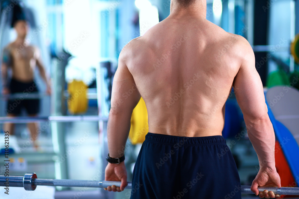 Fototapeta premium Young man lifting the barbell in gym with instructor