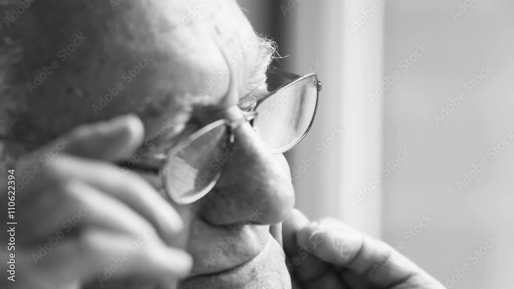 Black and white portrait of sad elderly man sitting by the window