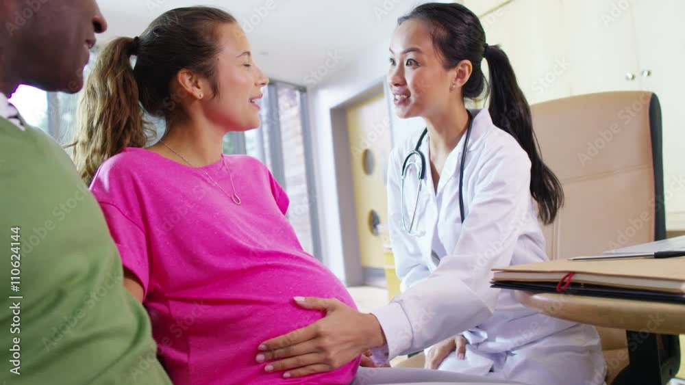 Friendly doctor talking to couple who are expecting a baby Friendly doctor talking to couple who are expecting a baby
