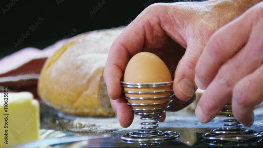  Close up on hands preparing breakfast of boiled eggs and rustic bread