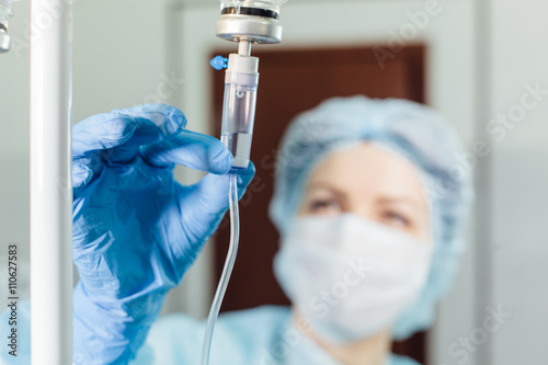 Nurse connecting an intravenous drip in hospital room. photo
