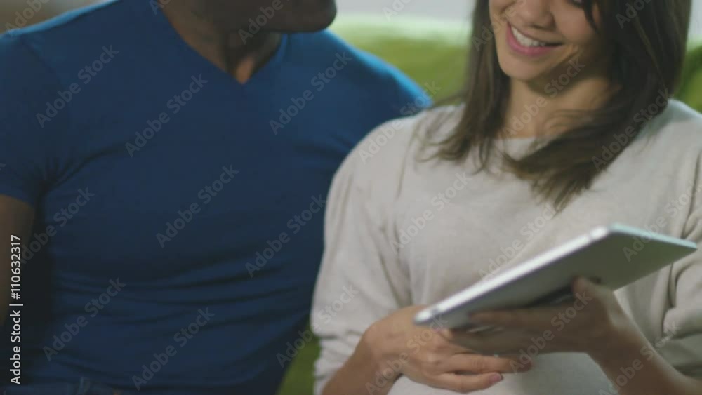 Affectionate pregnant couple relaxing at home looking at scan of the baby Affectionate pregnant couple relaxing at home looking at scan of the baby