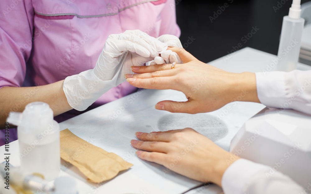 Obraz premium Manicure care procedure, Close-up photo Of Beautician Hand Painting Nails Of Woman In Salon