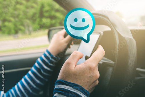 Female driving car and receiving smiley emoticon message on smar photo