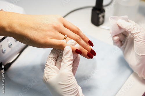 Manicure care procedure  Close-up photo Of Beautician Hand Painting Nails Of Woman In Salon