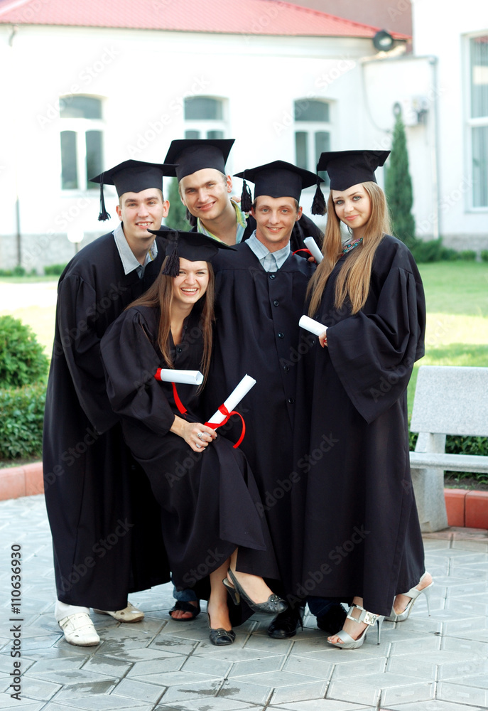 Graduates with diplomas in their hands smile and embrace