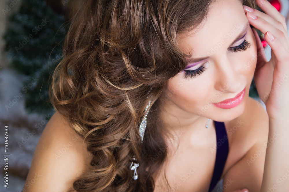 Fototapeta premium Portrait of beautiful elegant young woman in gorgeous evening dress over Christmas background.