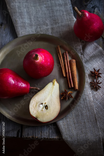 Obraz na plátně Pears and cinnamon stics on metal tray.