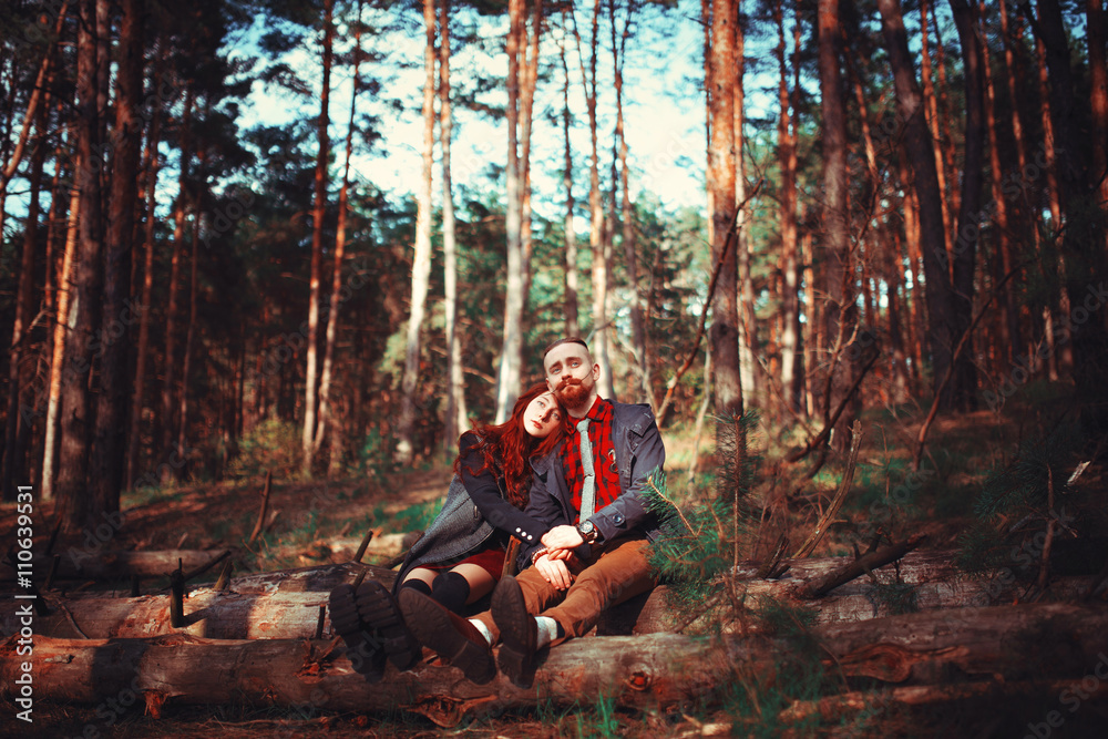 The red-haired guy with a beard and curly red-haired girl on the background of fabulous scenery of nature. Beautiful loving couple on a walk in the woods. The red-haired guy with a beard and curly red-haired girl on the background of fabulous scenery of nature. Beautiful loving couple on a walk in the woods.