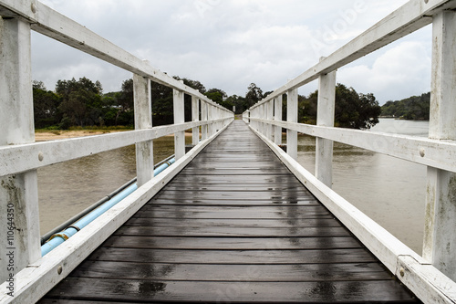 фотографія White timber pedestrian bridge crossing on an overcast and drizzly day - no peop