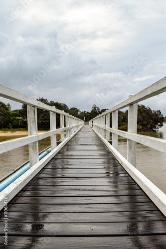 Vászonkép White timber pedestrian bridge crossing on an overcast and drizzly day - no peop