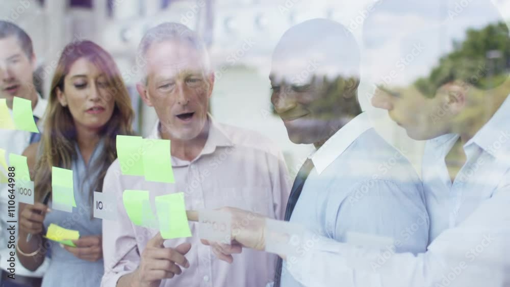 Mixed ethnicity business team brainstorming for ideas with sticky notes Mixed ethnicity business team brainstorming for ideas with sticky notes