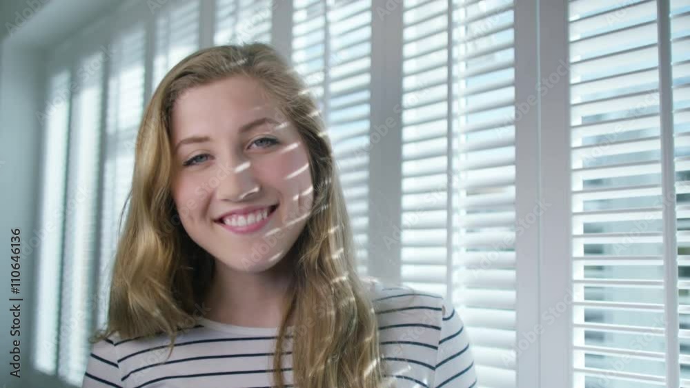 Portrait of smiling girl standing next to window on a sunny day Portrait of smiling girl standing next to window on a sunny day