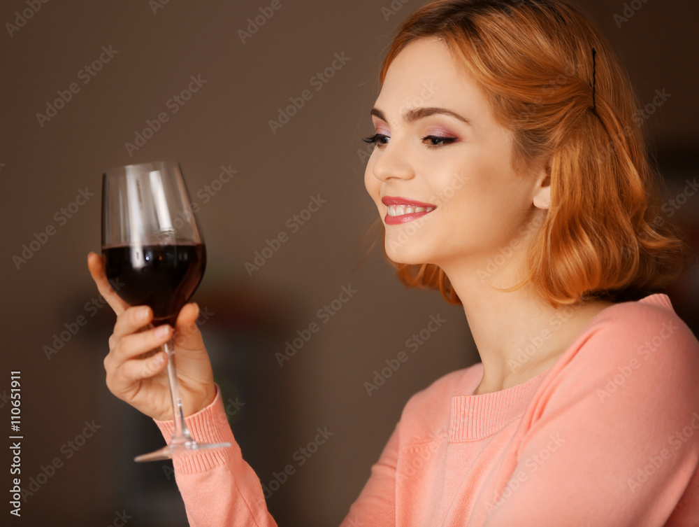 Young woman with glass of red wine on blurred background Young woman with glass of red wine on blurred background