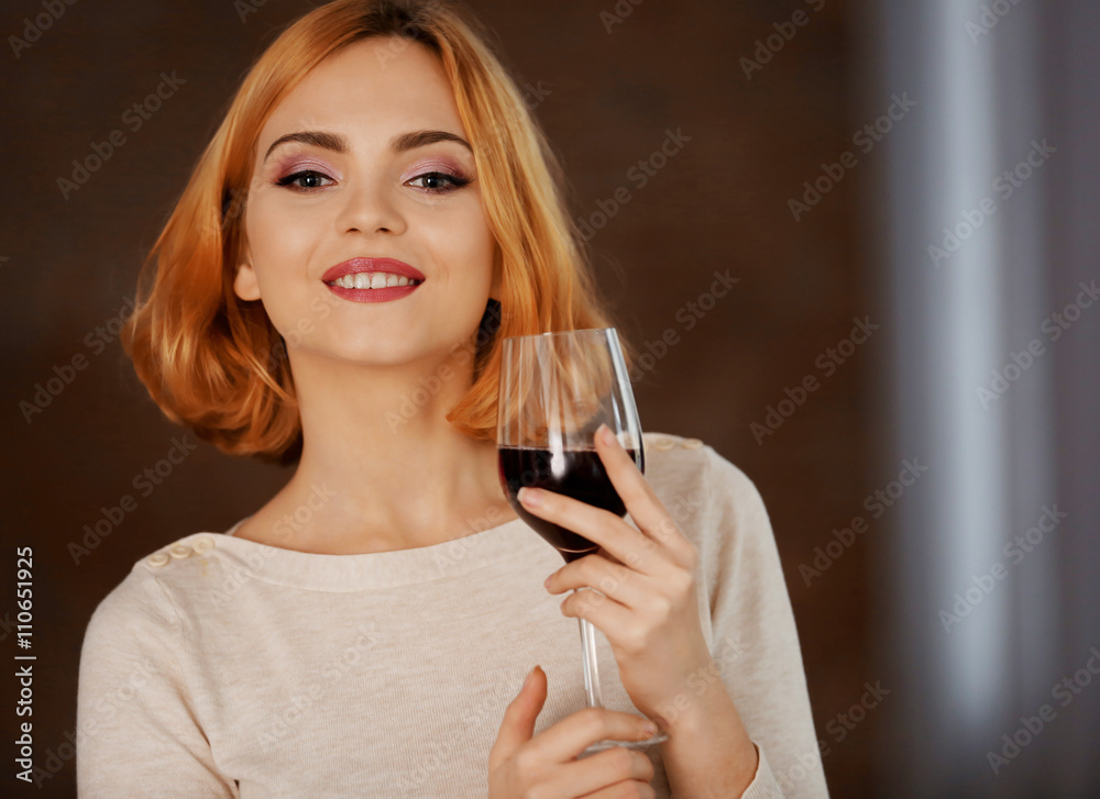 Young woman with glass of red wine on blurred background Young woman with glass of red wine on blurred background