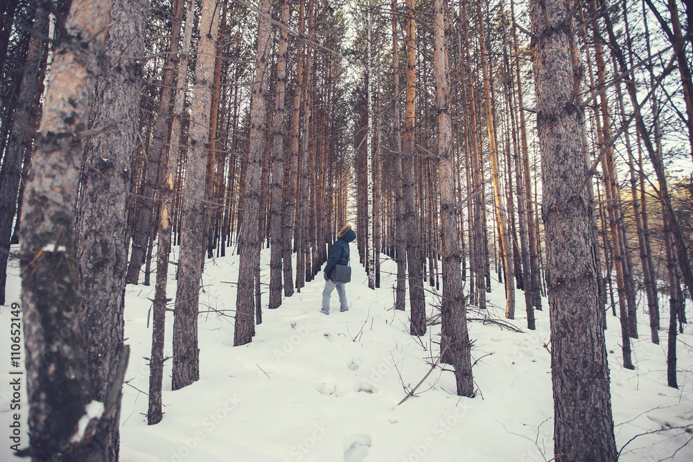 a man in a hood looking at forest plantations in the winter