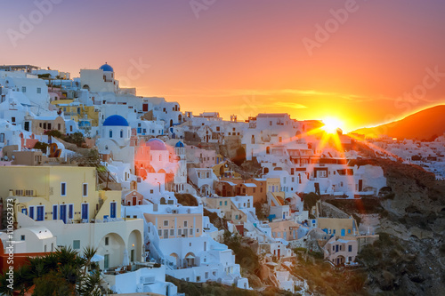 Old Town of Oia on the island Santorini, white houses and church with blue domes at sunrise, Greece