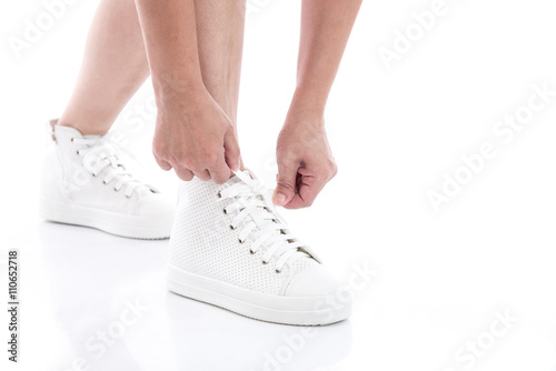 Asian woman tying laces in her white sneakers
