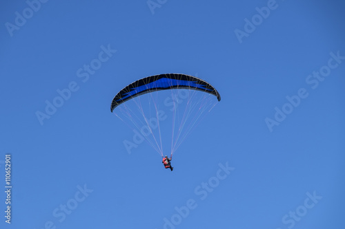 Paraglider gently floating in clear blue sky