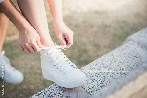 woman in white sneakers walking under sunlight