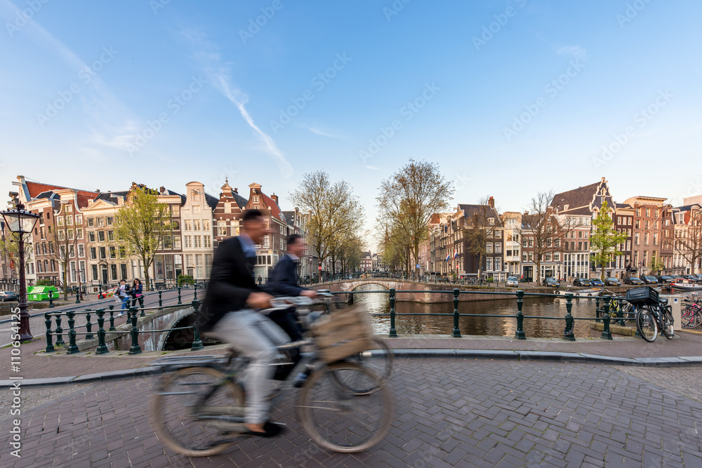 Naklejka premium Ludzie przejeżdżający na rowerze ulicami miasta w piękny letni dzień