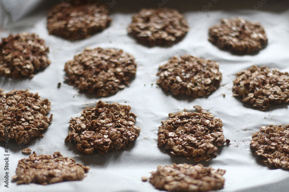 Healthy cookies prepared with oatmeal, banana and cocoa powder. Organized on parchment paper before baking. Selective focus.