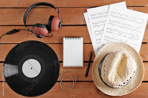 Headphones, music sheets and straw hat on wooden surface, top view