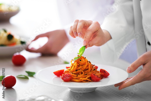 Chef hands preparing delicious cold pasta salad on the table closeup