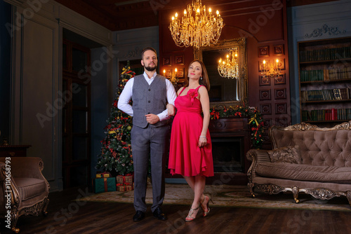 Beautiful well-dressed young couple standing on a steps in luxury interior
