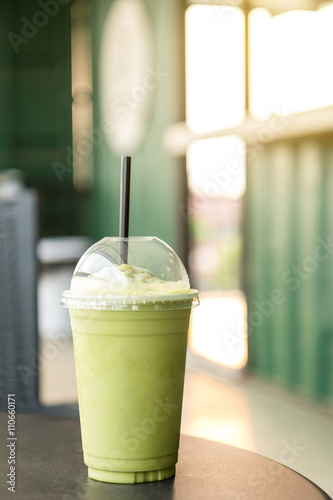 Green tea matcha smoothies in plastic cup. Interior coffee shop. Condensation on a cup (Selective focus and shallow depth of field)