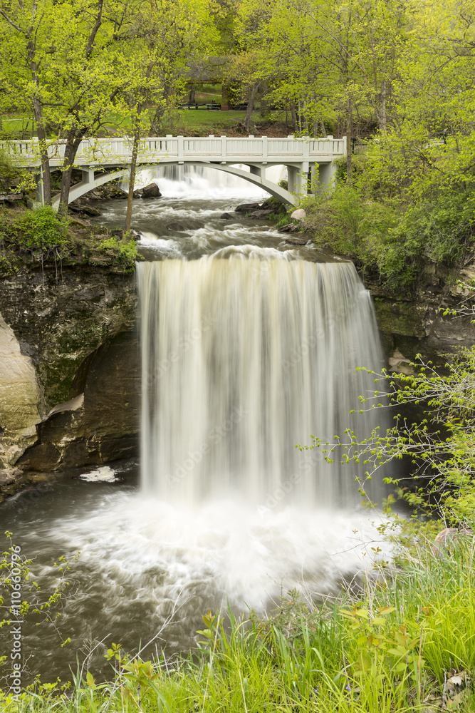 Obraz premium Minneopa Falls / A waterfall with a footbridge during spring.