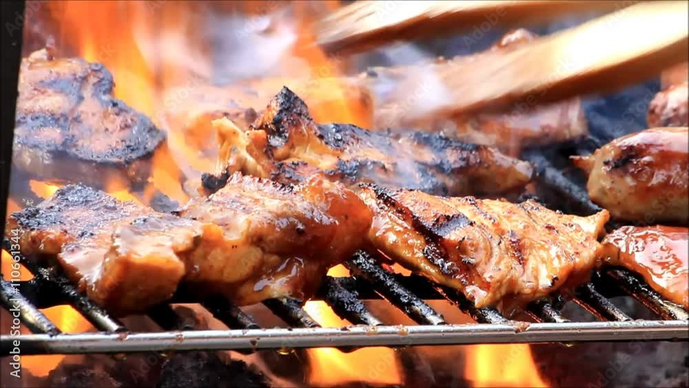 pork and turkey meat on the grill with flames
