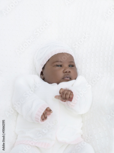 Adorable one-month-old baby girl lying in her bed